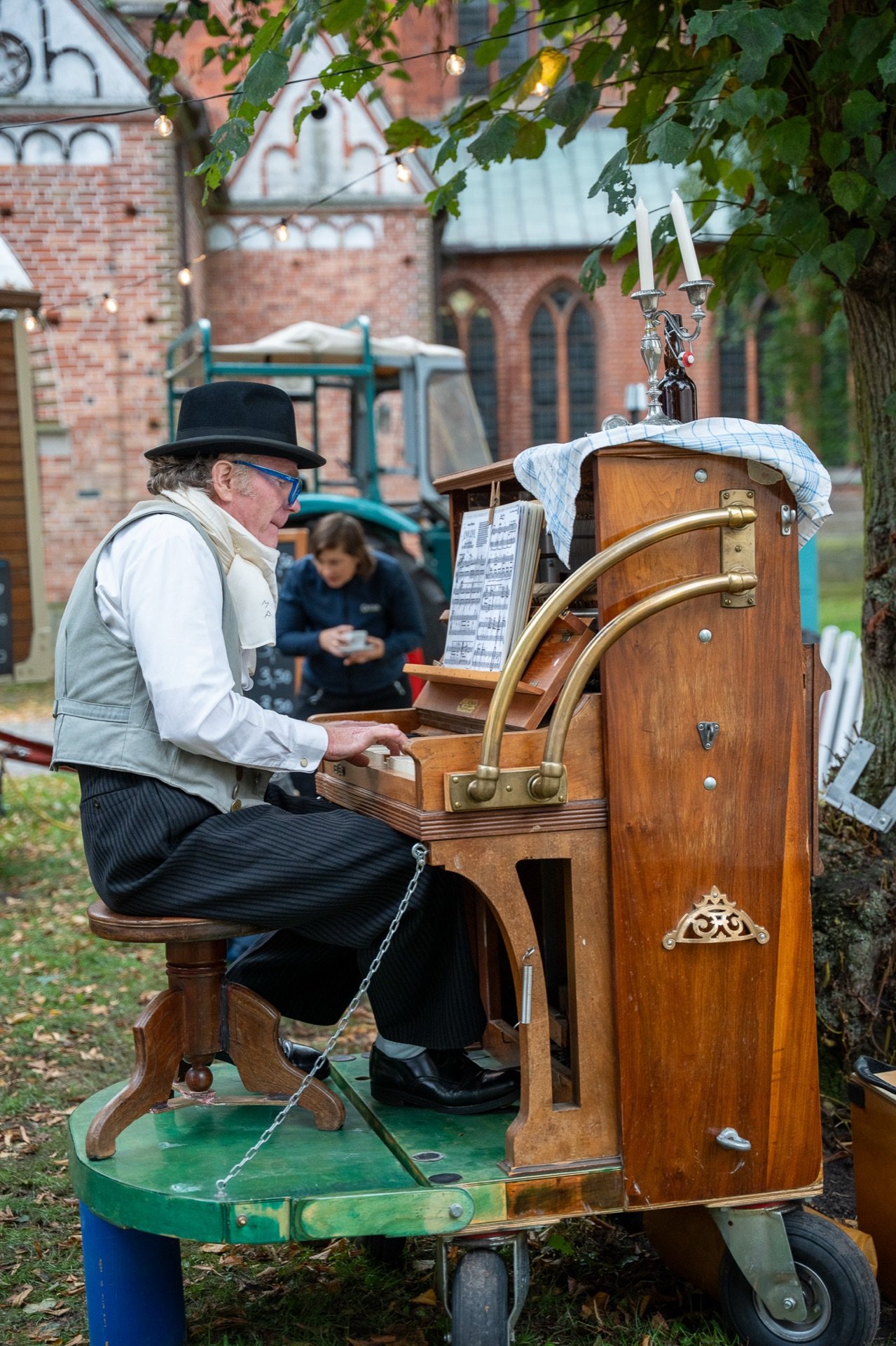 Musiker mit Melone spielt auf einem historischen Klavierwagen auf dem Vorplatz, dahinter der Lübecker Dom