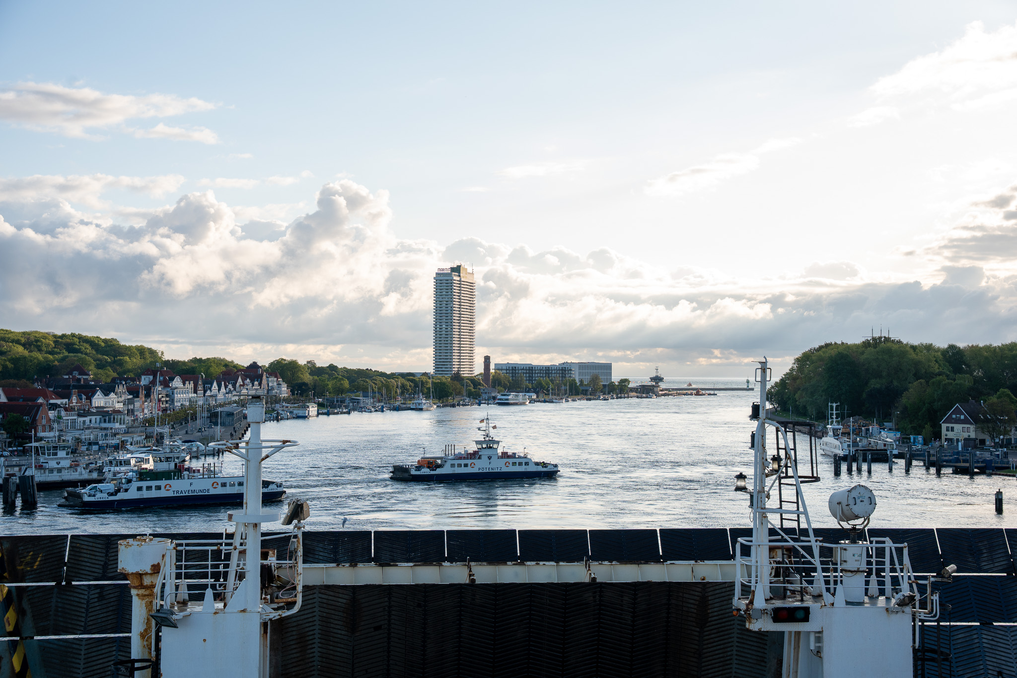 Blick vom Fährdeck auf die Travemünder Hafeneinfahrt mit dem Maritim-Hochhaus und einem Lotsenboot