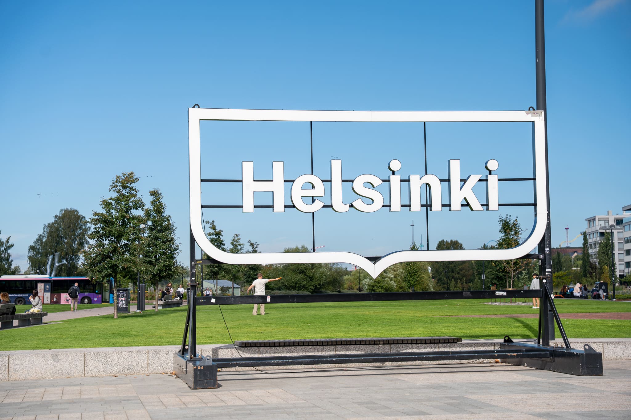 Großes weißes Helsinki-Schild in Form einer Sprechblase auf einer Rasenfläche im Park