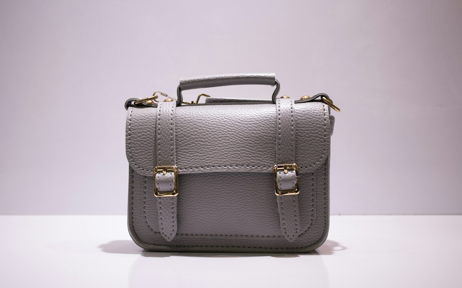 Graue Ledertasche mit goldenen Schnallen