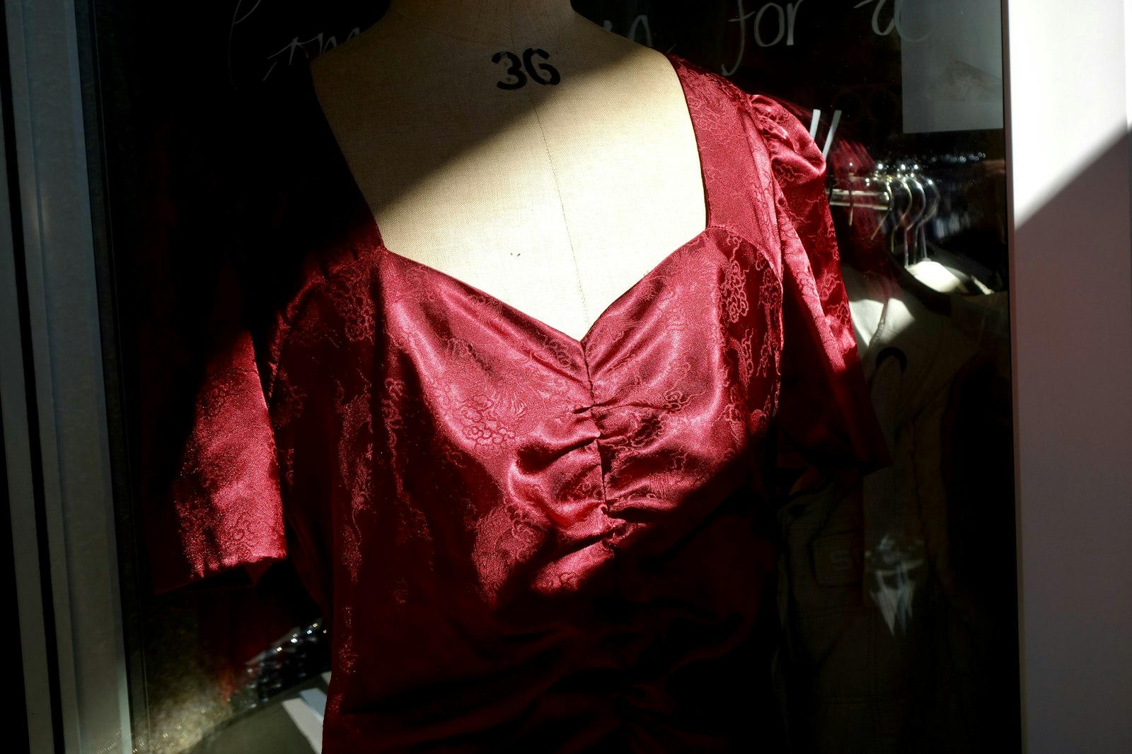 Schaufensterpuppe mit rotem Satin-Oberteil im Sonnenlicht