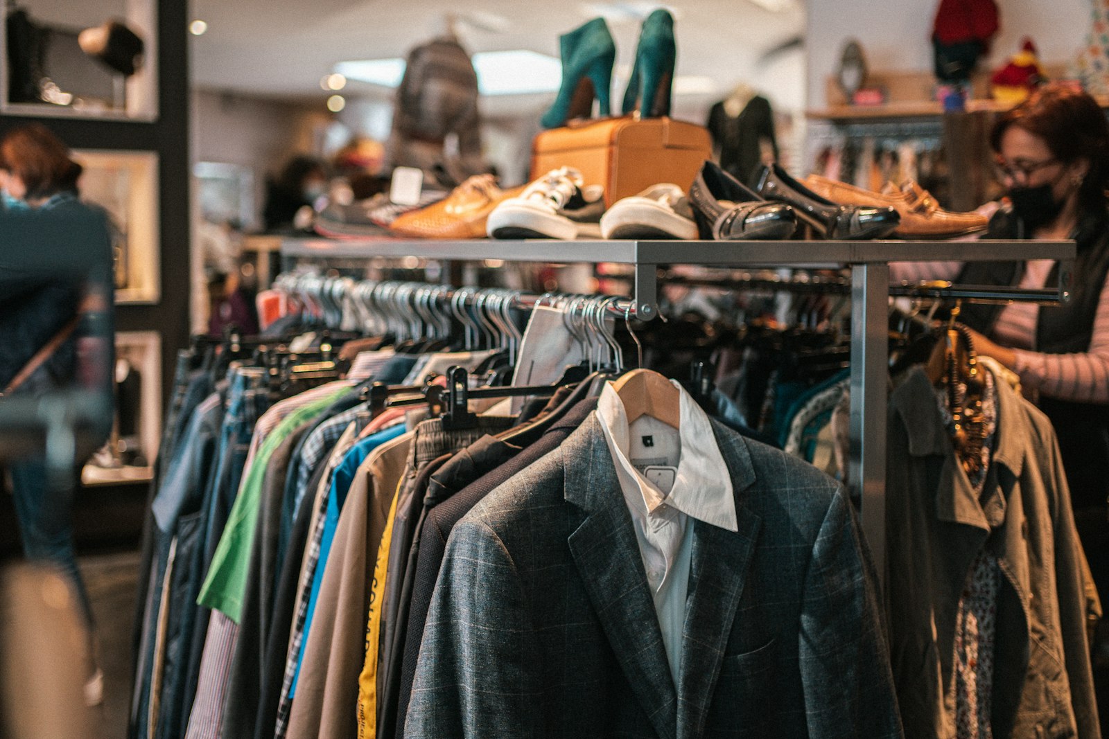 Kleiderstange mit Secondhand-Mode und Schuhregal in einem Laden